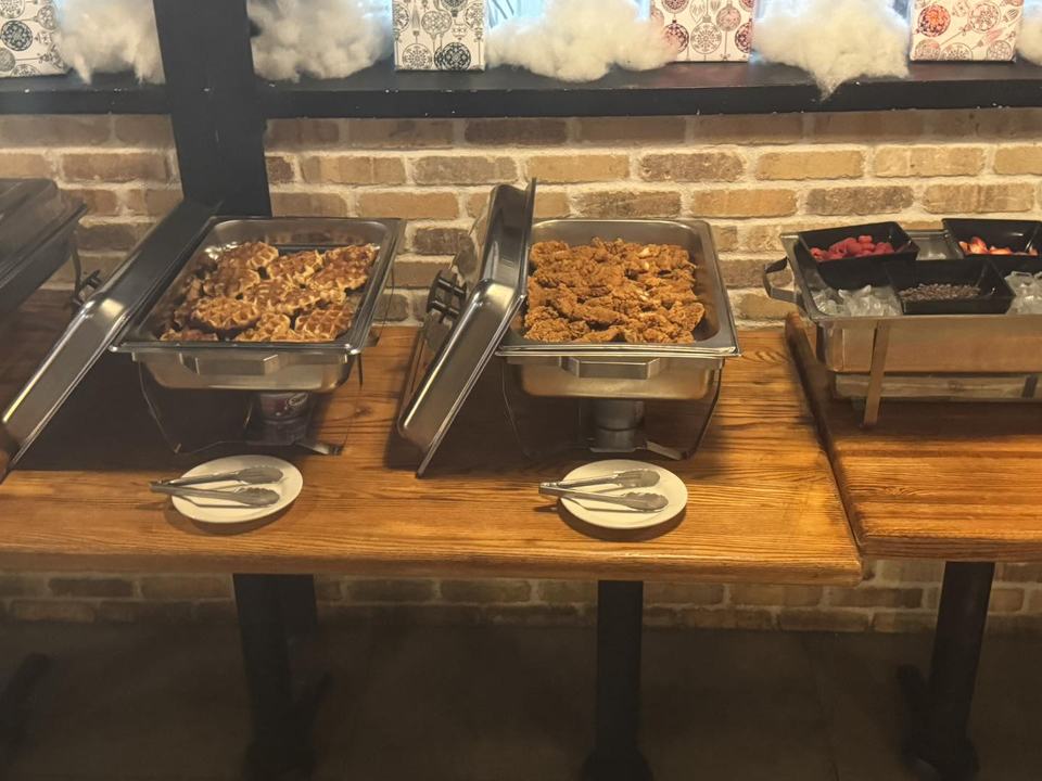 Hot brunch pans in chafing dishes on the buffet, plates stacked beside them.