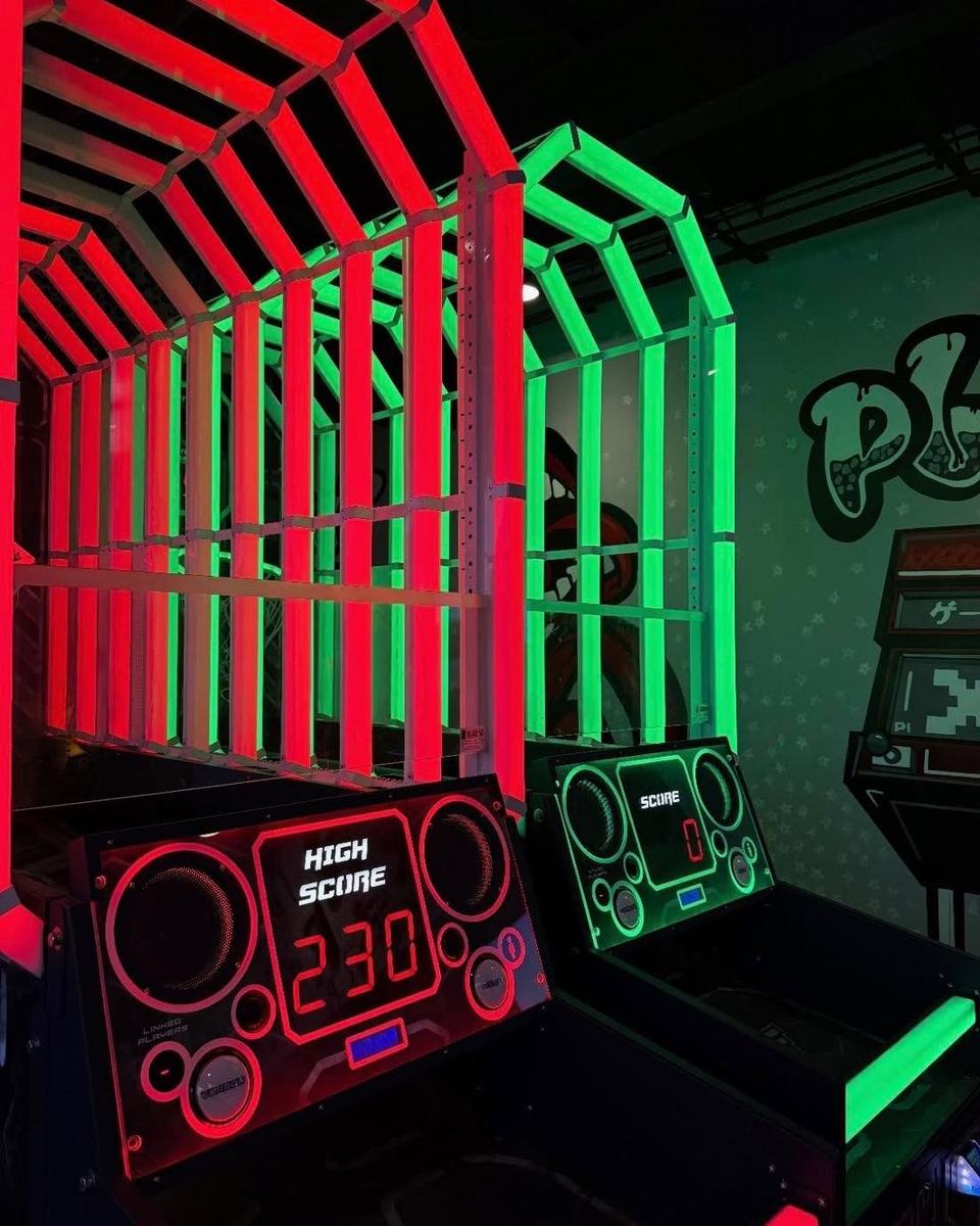 Wildstyle PLAY lettering sprayed on the white wall behind the neon red and green basketball hoops.